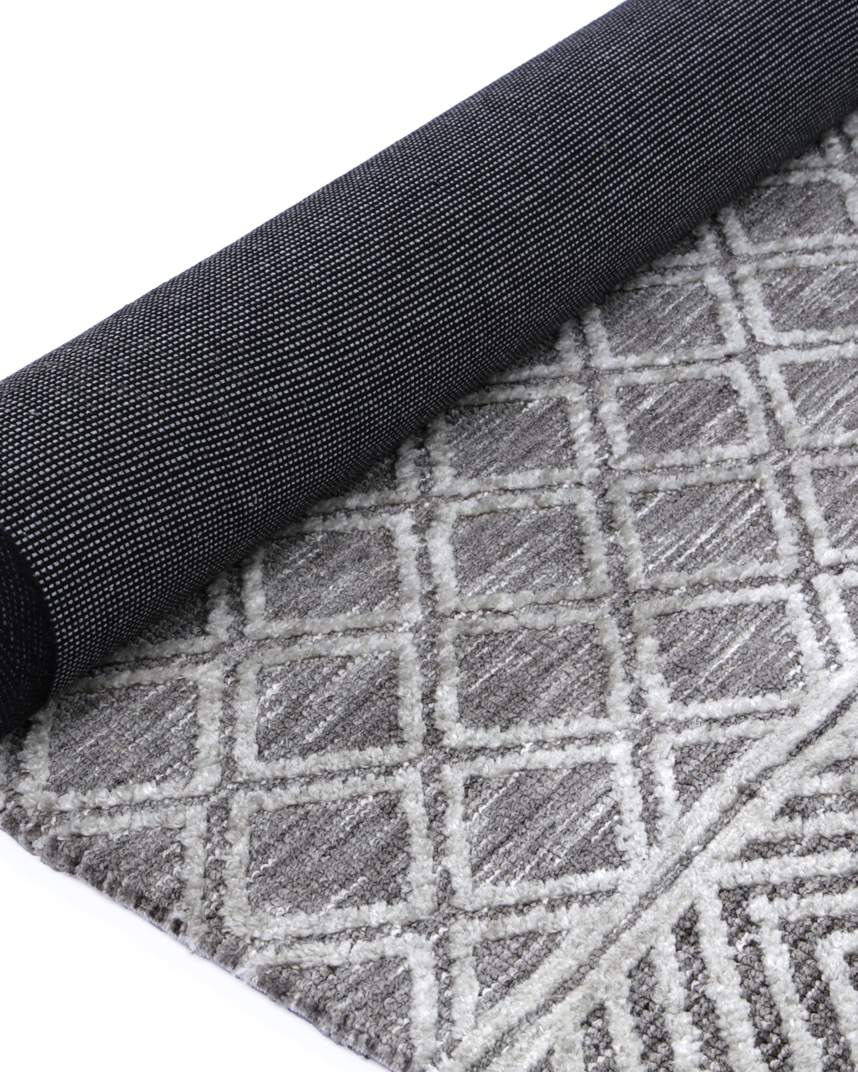 Alayah Diamond Trellis Silver Rug rolled with dark cotton back on white flooring
