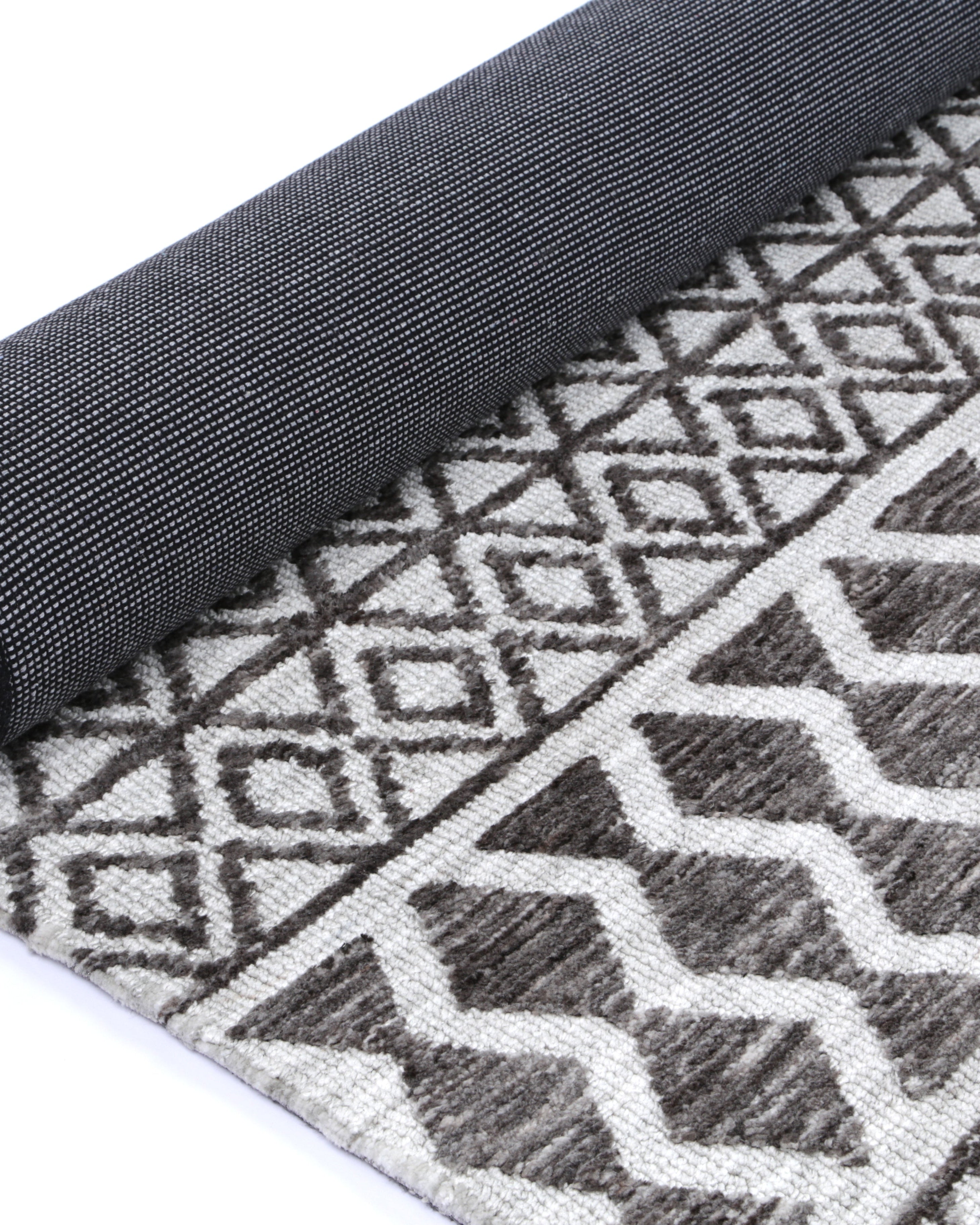 Alayah Tessellations grey & taupe Rug rolled showing dark cotton backing
