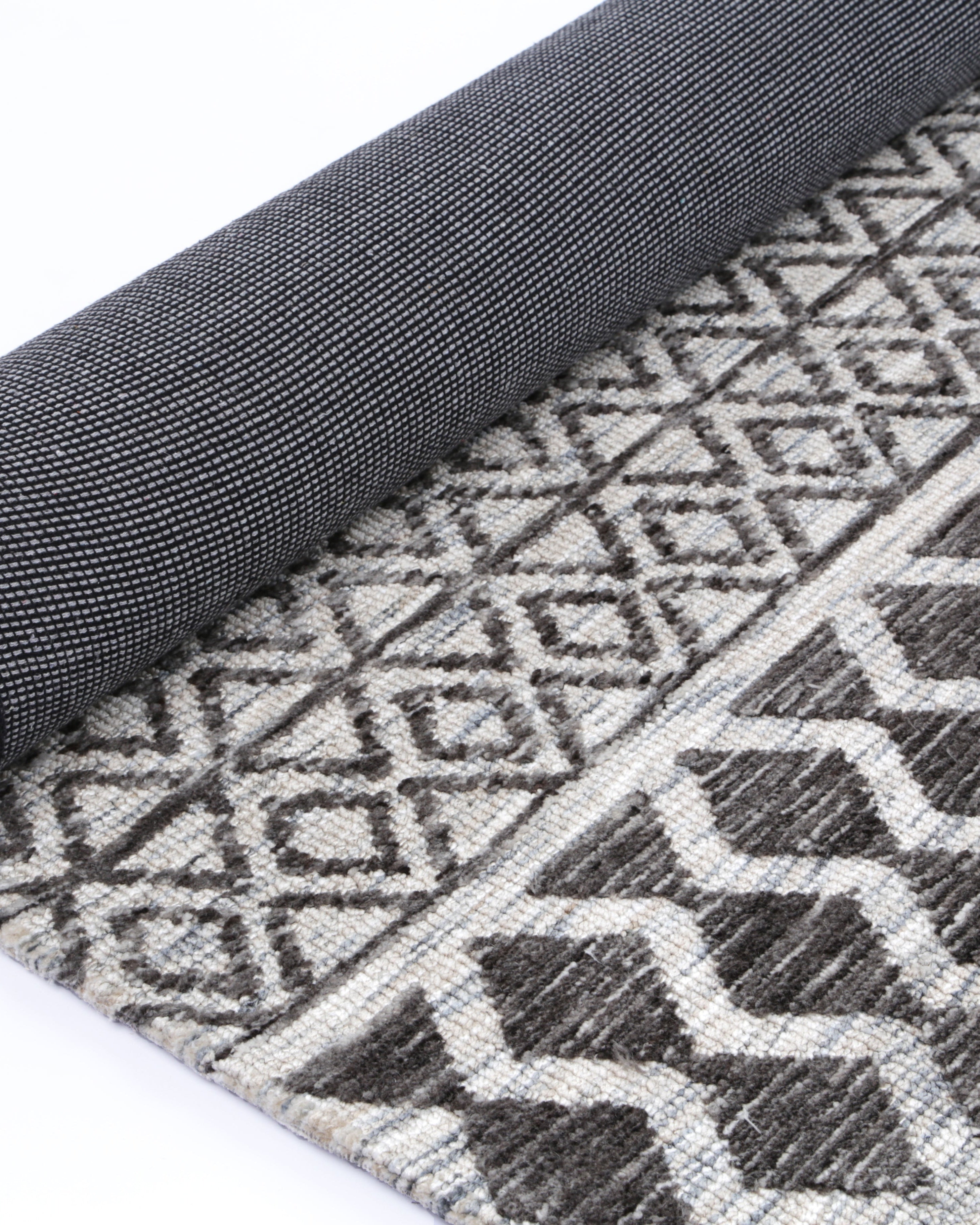 Alayah Tessellations silver Rug rolled exposing dark cotton backing