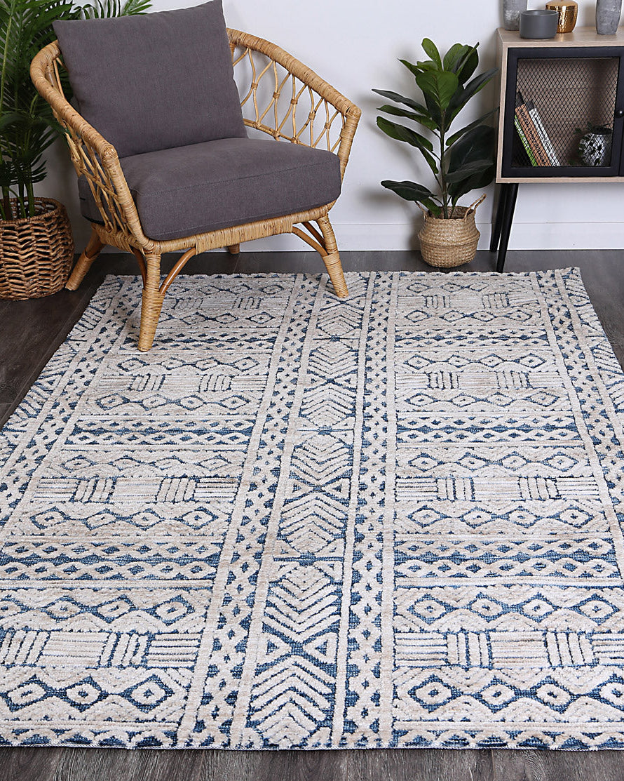 Alayah Tribal teal Rug on dark flooring with wicker backers and grey chair
