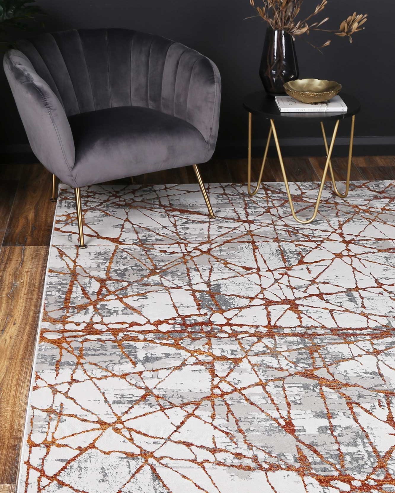 Almada Geometric Orange Rug in lounge room charcoal velvet chair on timber flooring with granite side table