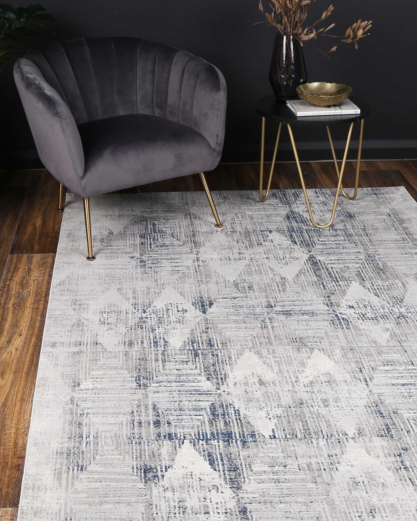 Almada indigo and ash Diamond Rug on timber flooring with grey arm chair with gold legs, black walls and a brass bowl
